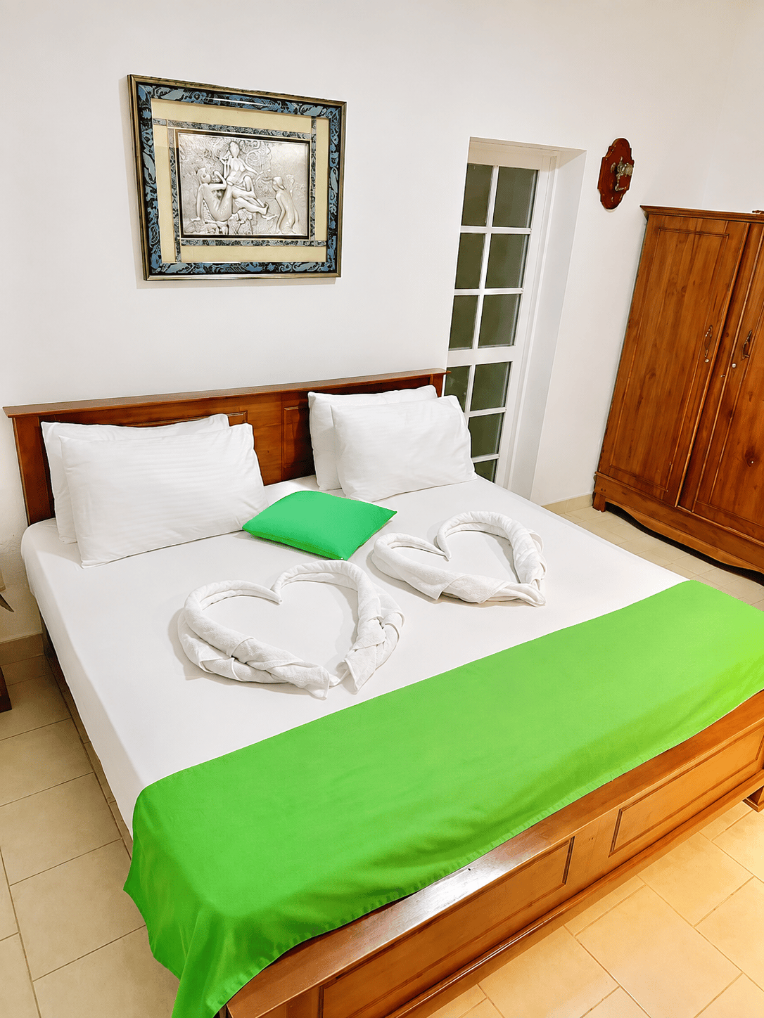 Bedroom with full bed, towels, and wooden wardrobe