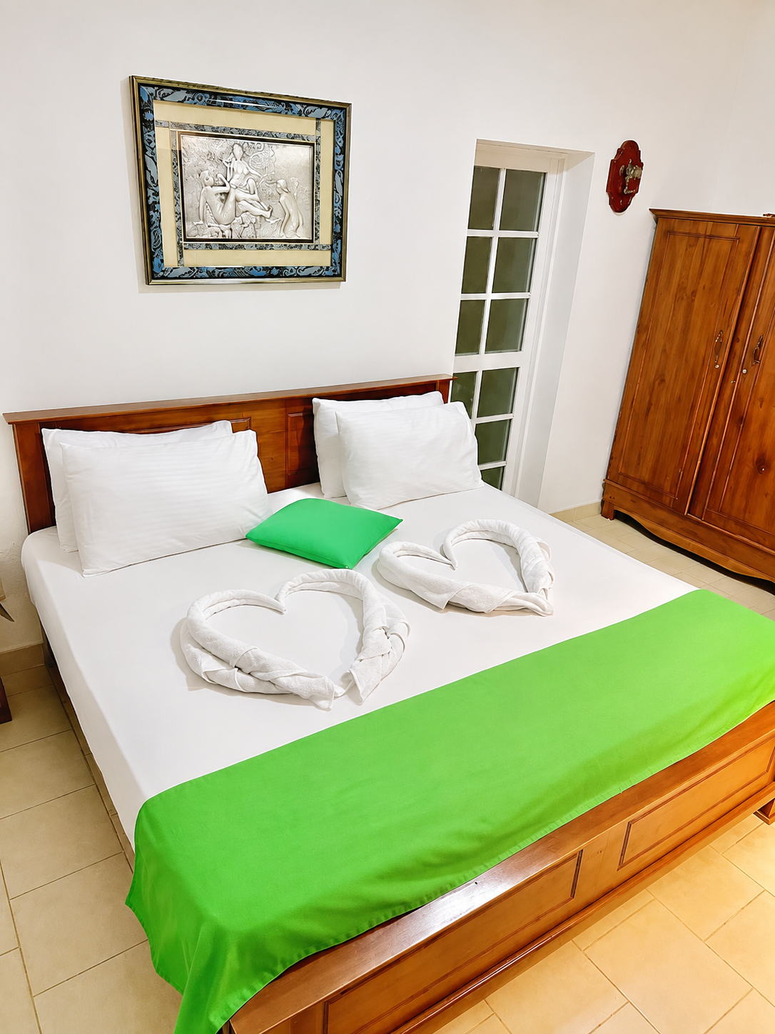 Bedroom with full bed, towels, and wooden wardrobe
